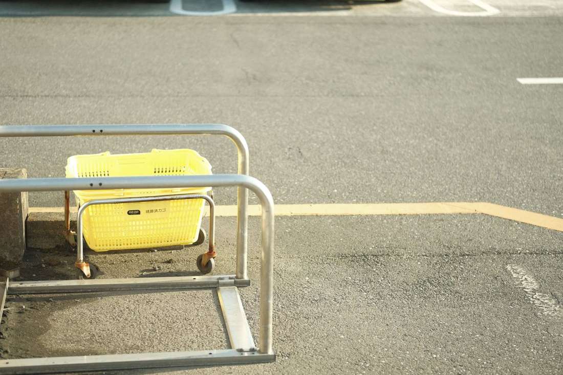 駐車場に置かれた黄色い買い物かごとカート